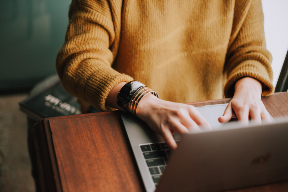 Photo of a person sat at a table, using a laptop