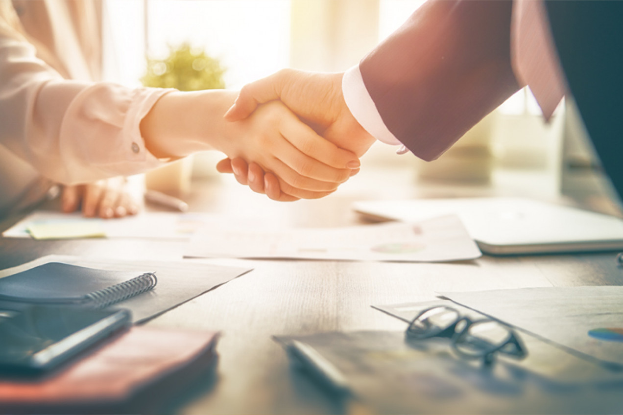 Photo of two people shaking hands across a desk