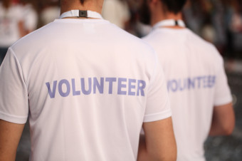 Photo of two people facing away from the camera, with volunteer written on the back of their shirts