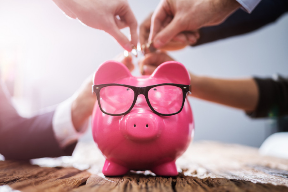 Photo of multiple people putting coins in a piggy bank