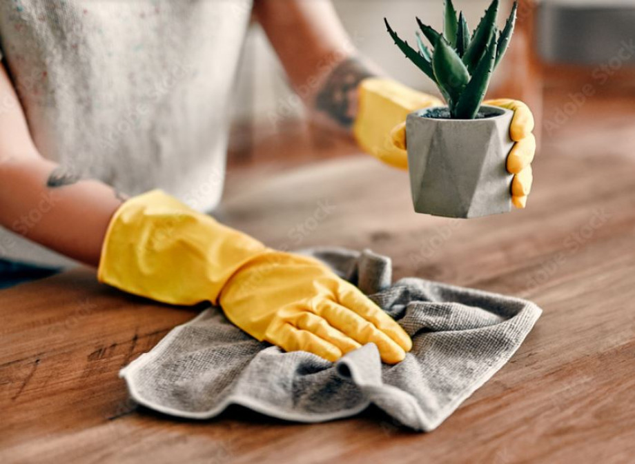 Photo of someone wearing rubber gloves and cleaning a worktop