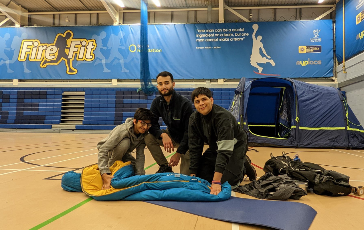 Photo of three people holding a sleeping bag